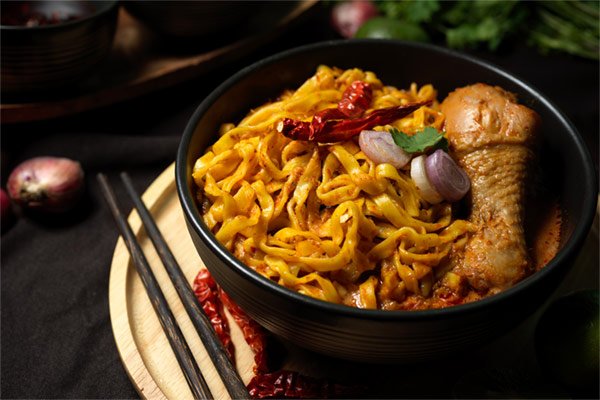 khao-soi-kai-tasty-spicy-creamy-yellow-curry-noodles-with-chicken-drumstick-black-bowl